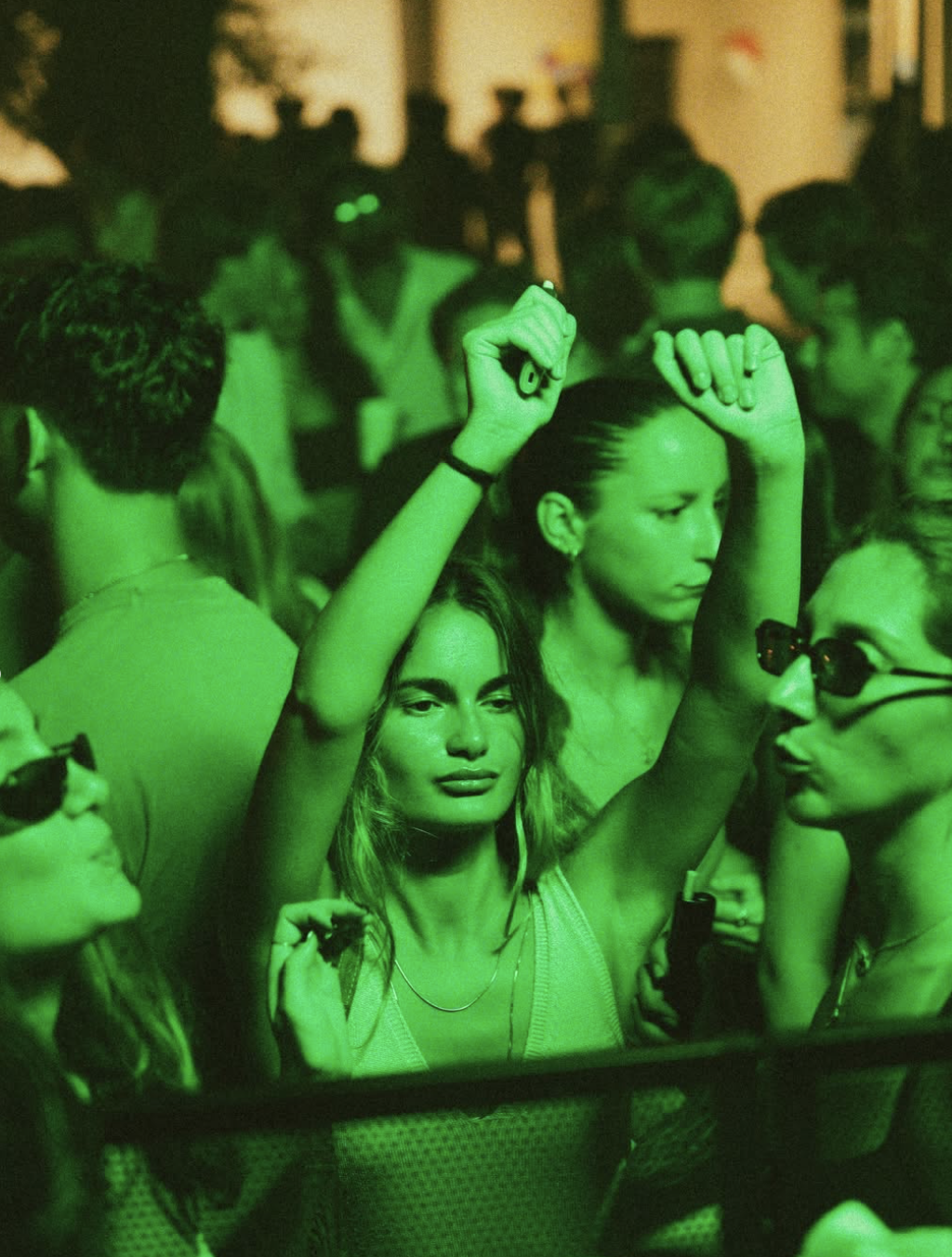 Crowd dancing under green lights
